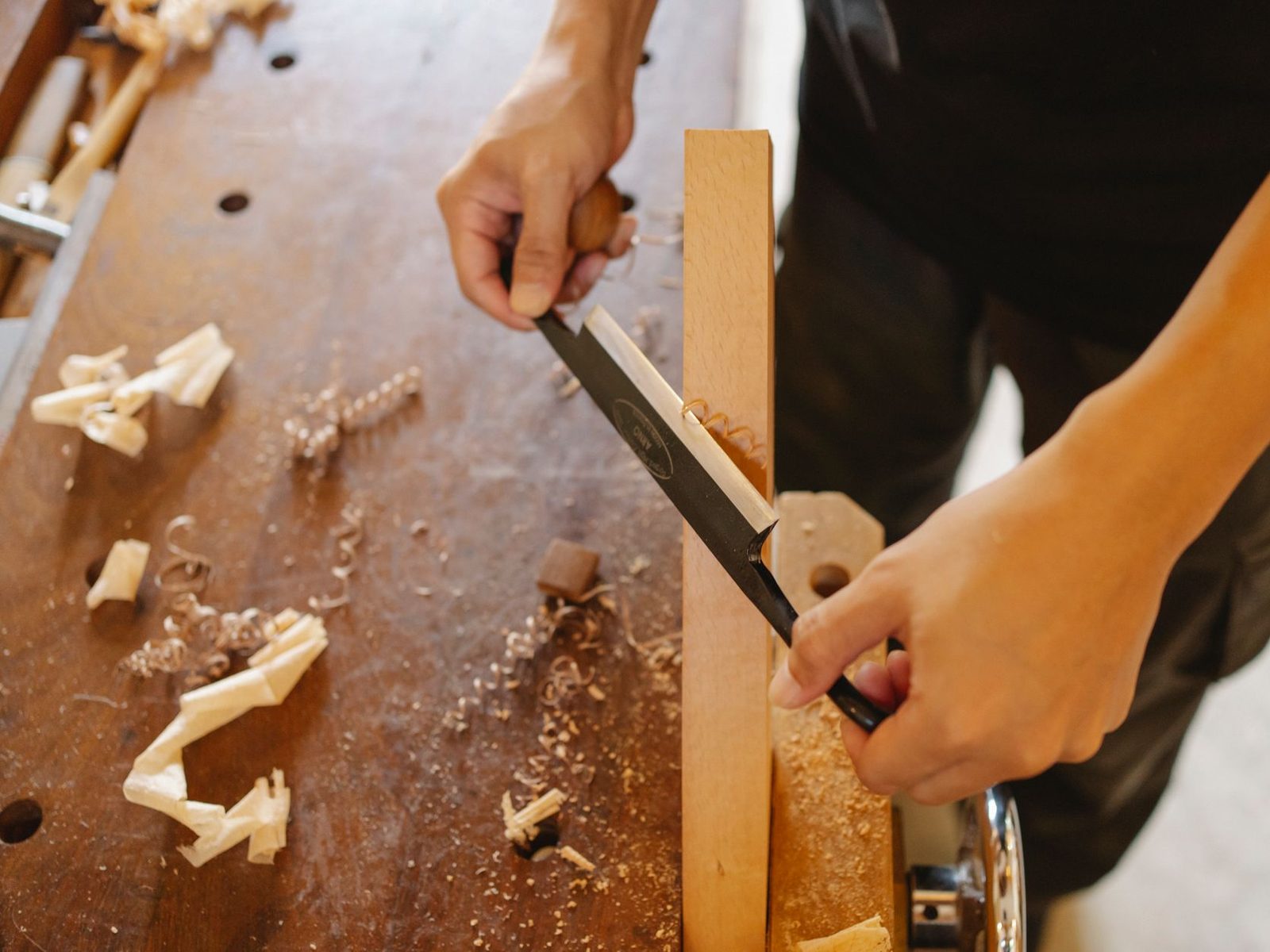 Close-up of a joiner shaping a solid oak frame joint in the workshop.