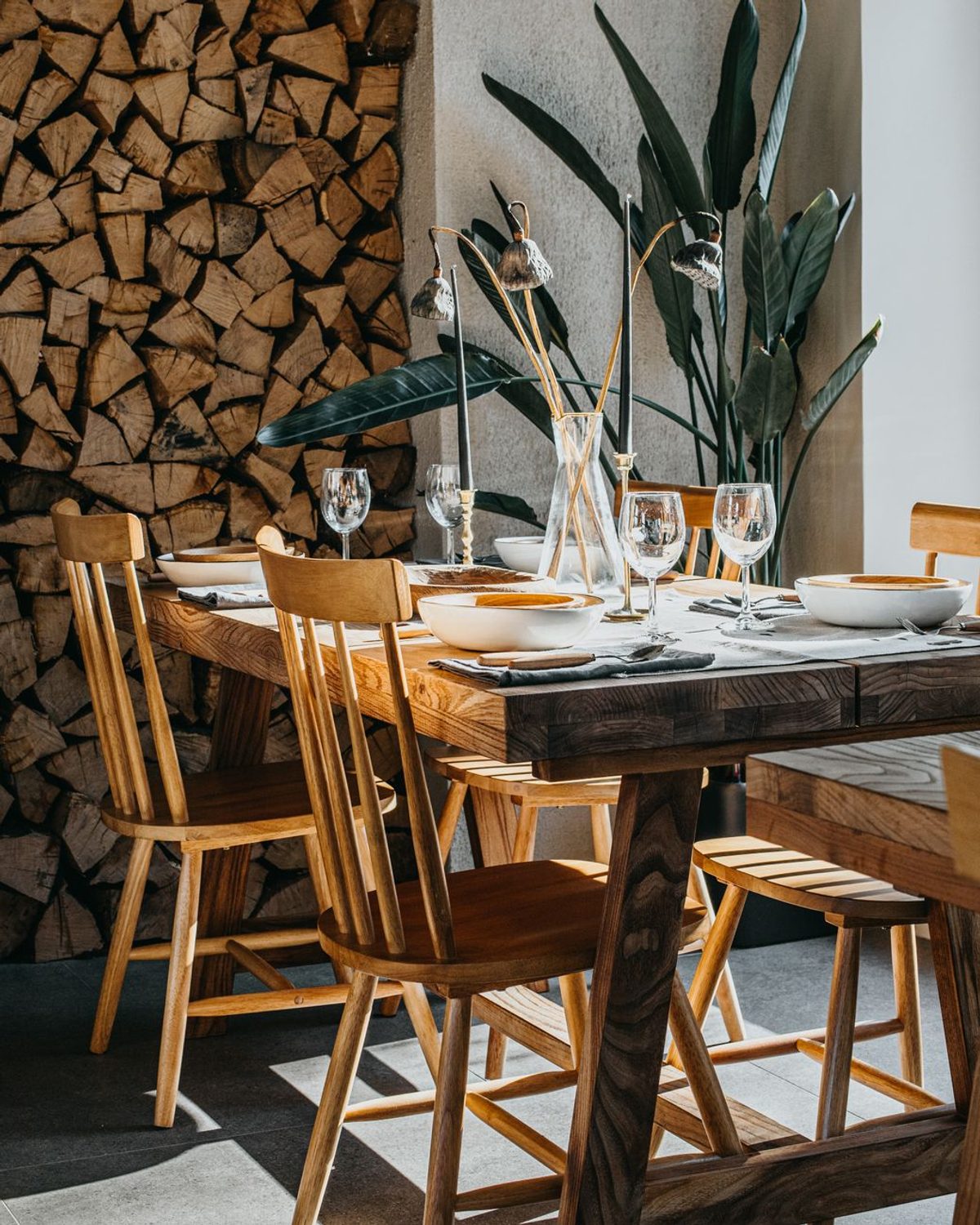 Doma Dining Table in natural ash with a matte black steel base, set for a hospitality dining room.