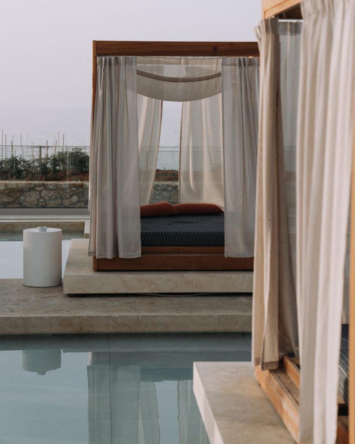 Niwa Outdoor Lounge in natural teak with sand rope weave, poolside on a resort terrace.